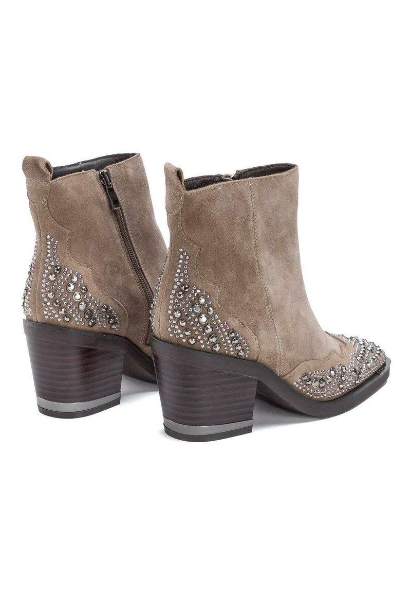 Botines de ante en marrón claro con rhinestones decorativos a lo largo de los lados y un tacón de madera apilada de color marrón. Cierre de cremallera lateral.