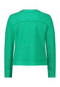 Grön, texturerad jacka med rak skärning, långa ärmar och rundad krage. Synliga sömnadsdetaljer längs sömmarna och fållen.