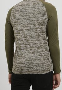 Långärmad skjorta med olivgröna ärmar och en texturerad grå kropp med horisontella mönster. Material av bomullsblandning, figursydd design.