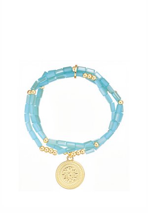 Dobbelttrådet armbånd med lyseblå rektangulære perler, små gyldne runde perler og en rund gylden medaljonsvedhæng med et præget solmotiv.