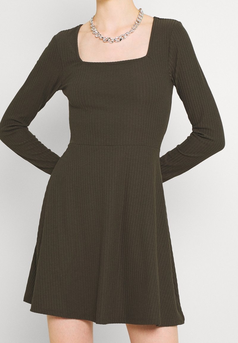 Robe côtelée vert olive foncé avec un décolleté carré, des manches longues et une jupe évasée ; présente une texture lisse et de subtils détails de couture.