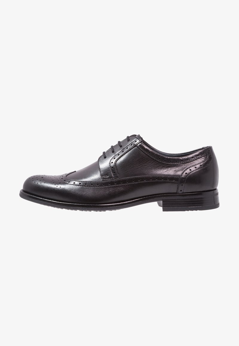 Chaussure habillée en cuir noir avec des détails brogues, un bout arrondi et cinq œillets. Présente une texture lisse et un petit talon empilé.