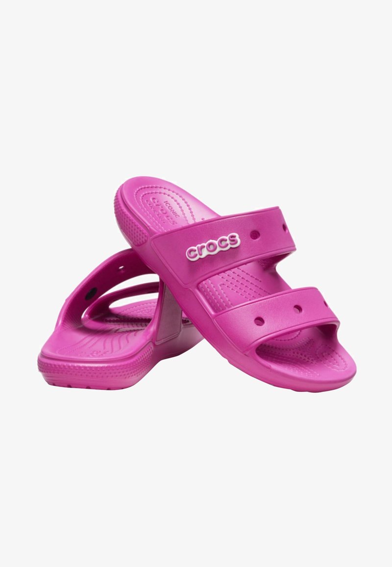 Sandales en caoutchouc roses avec des doubles sangles et des trous de ventilation, présentant une semelle intérieure texturée et un logo "CROCS" bien en vue sur le côté.