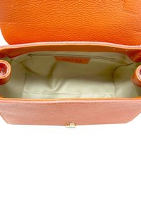 Bolso de mano de cuero naranja con exterior texturizado, herrajes dorados y un forro de tela beige. El interior cuenta con un bolsillo con cremallera y amplio espacio.