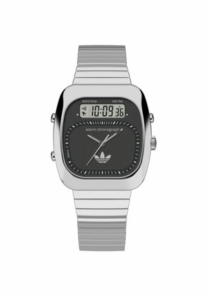 Ceas digital din metal argintiu, cu un cadran pătrat, fundal negru, markeri albi pentru ore și logo-ul Adidas în partea de jos.
