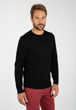 Schwarzer Pullover mit langen Ärmeln, Rundhalsausschnitt, geripptem Saum und glatter Textur. Kombiniert mit roten Hosen, verfügt über ein kleines Logo auf dem Ärmel.