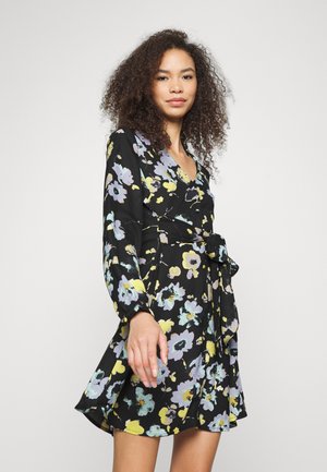 Vestido preto floral com mangas compridas, apresentando um design envolvente, decote em V e uma cintura atada. Flores em amarelo, lavanda e verde-água criam um padrão vívido.