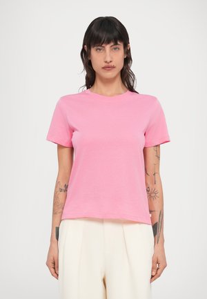 Short-sleeve, round-neck T-shirt in bright pink cotton. Features a relaxed fit with a straight hem, worn with beige pleated trousers.