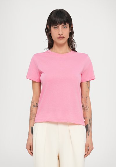 Κοντομάνικο T-shirt με στρογγυλή λαιμόκοψη από φωτεινό ροζ βαμβάκι. Διαθέτει άνετη εφαρμογή με ίσια τελείωμα, φορεμένο με μπεζ πλισέ παντελόνι.