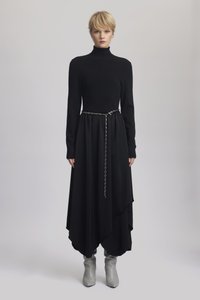 Svart kjole med en tettsittende strikket topp og flytende skjørt. Har et kjede belte. Kombinert med grå knelange, slouchy støvler. Jevn tekstur.