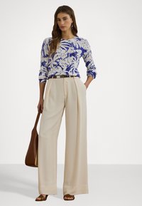 Knitted sweater with blue and white floral pattern, paired with high-waisted beige wide-leg trousers. Brown belt and handbag.