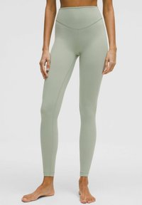 Leggings s visokim strukom od svijetlozelene tkanine s glatkom teksturom, s detaljima šavova i prilagođenim dizajnom.