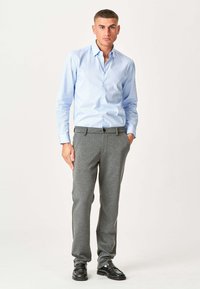 Lyseblå, langærmet skjorte med knapper, grå skræddersyede bukser og sorte dress sko. Glat tekstur, tætsiddende design og klassisk stil.