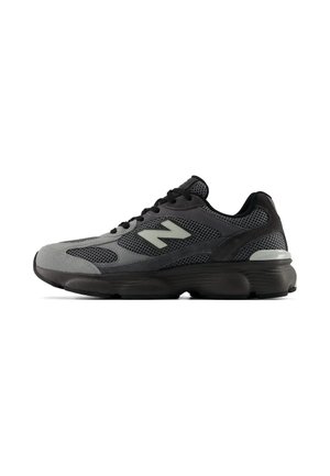 Sneaker sportiva nera e grigia con dettagli in mesh e suede, suola spessa e logo riflettente "N" sul lato.