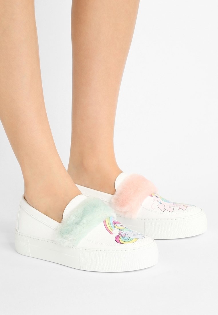 Białe buty wsuwane z kolorowymi wzorami jednorożców, ozdobione puszystymi pastelowymi akcentami w kolorze mięty i różu na paskach. Grube białe podeszwy.