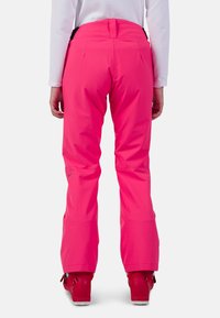 Klart rosa skidbyxor med rak skärning, tillverkade av slitstarkt, vattenavvisande material. Har justerbar midja och logotypdetalj på sidan.