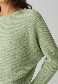 Hellgrüner Strickpullover mit strukturiertem, geripptem Design; weiter Ausschnitt und lange Ärmel; weiches, gemütliches Material.