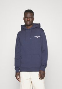 Felpa blu navy in misto cotone, con tasca a marsupio frontale, cappuccio con coulisse e logo sul petto. Tessuto testurizzato.
