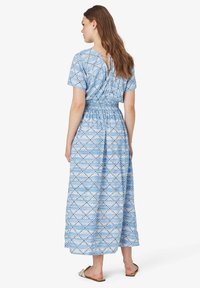 Maxikleid mit blauem Muster, kurzen Ärmeln, Raffung an der Taille und einem Bindeband im Rücken. Es hat ein geometrisches Design in Hell- und Dunkelblau.