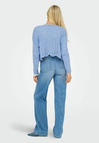 Maglione corto lavorato a maglia in azzurro chiaro con motivo testurizzato e bordo a scallop, abbinato a jeans in denim azzurro chiaro a vita alta.