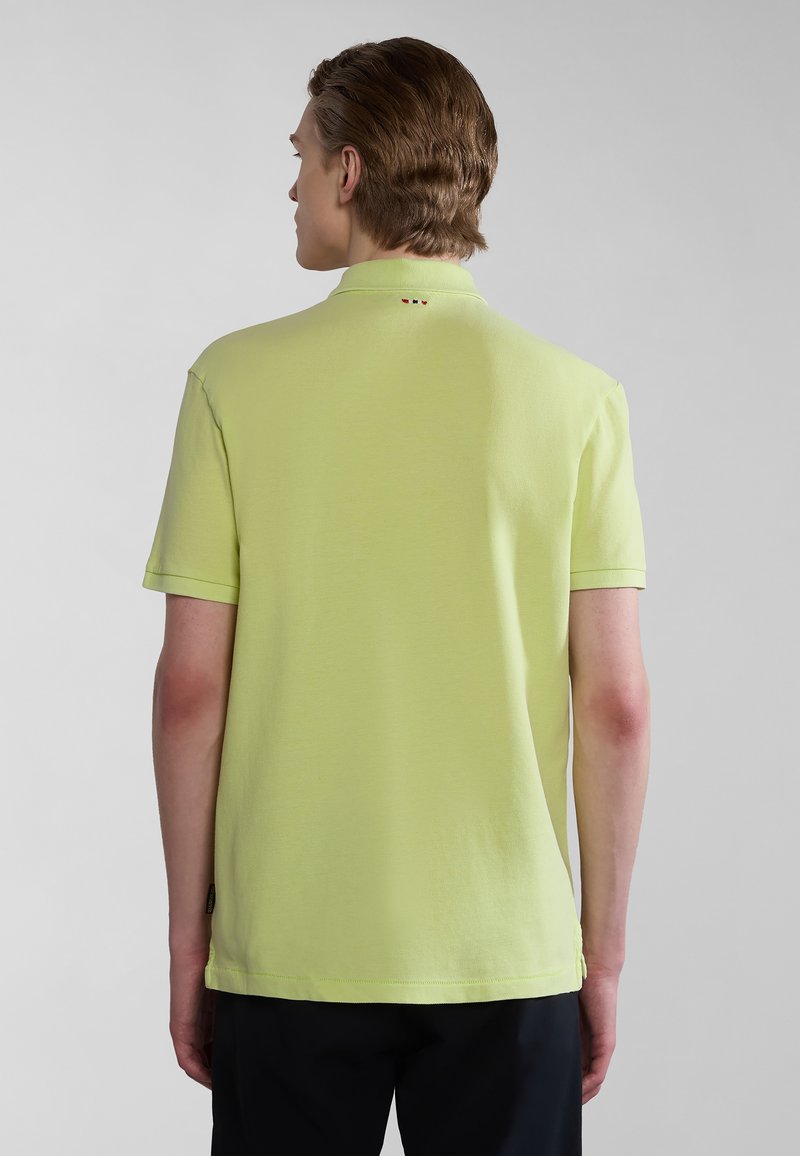 Polo shirt verde lime con maniche corte, un colletto e tre bottoni decorativi sul retro. Tessuto liscio e senza loghi visibili.