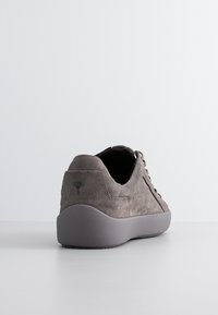 Zapatilla de ante gris con la parte trasera redondeada, cuello acolchado y suela de goma. Presenta costuras tonales y un logo sutil en el talón.
