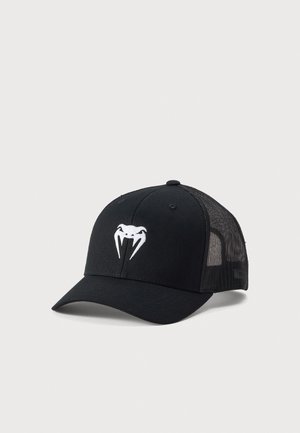 Gorra trucker negra de malla con visera curva y logo blanco de cabeza de víbora en el panel frontal, mostrada sobre fondo gris claro.