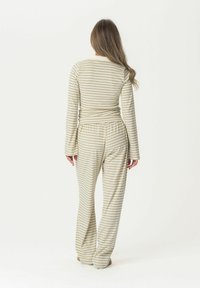 Conjunto de loungewear a rayas en verde apagado y crema, que incluye una camiseta ajustada de manga larga y pantalones sueltos con cintura elástica.