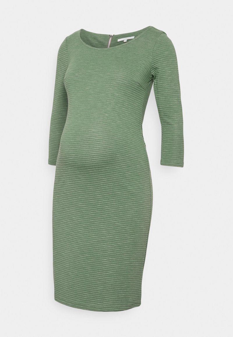Robe de maternité en tissu vert texturé, avec un décolleté arrondi et des manches trois-quarts, conçue pour s'adapter à un ventre en croissance.