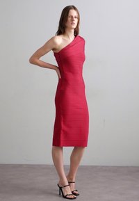 Rotes Ein-Schulter Bodycon-Kleid mit horizontaler Rippstruktur, knielanger Silhouette und figurbetontem Design. Schwarze, schnürbare High Heels.