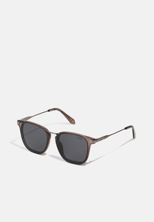 Brown square sunglasses with dark lenses, metal accents, and a sleek frame design. Model: Quay. Durable, lightweight construction.