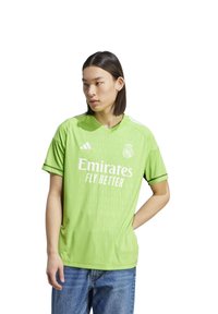 Camiseta de fútbol verde de manga corta con cuello en V. Presenta "Emirates Fly Better" en texto blanco, logo en el pecho y una textura sutil.