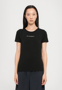 Svart kortermet t-skjorte i bomull med rund hals og en hvit logo "EA7 Emporio Armani" trykt på brystet.