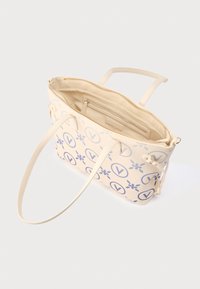 Beige håndtaske med blå blomster- og logomønstre, lynlås, inderlomme og dobbelte skulderstropper. Glat tekstur.
