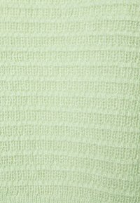 Ljusgrön texturiserad tyg med ett vävt mönster, med en mjuk, något upphöjd yta och jämn fördelning av garn.