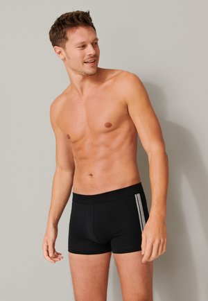 Svarta boxershorts med bred midjeband och silverfärgade sidostråk. Tyget ser slätt och elastiskt ut, utformat för komfort.