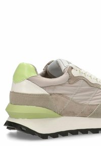 Zapatillas que presentan una mezcla de ante gris claro y cuero blanco. Con un talón verde brillante, paneles laterales texturizados y una suela de goma negra.
