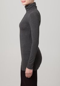 Šedý dlhý rukáv turtleneck top vyrobený z mäkkého, ľahkého materiálu s priliehajúcim strihom, ktorý má vysoký golier a bezšvové strany.