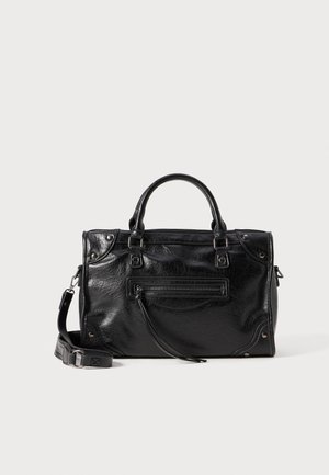 Black leather handbag with two short handles and a detachable shoulder strap. Features a front zip pocket and metal accents. Textured surface.