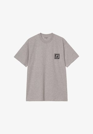 Camiseta de algodón gris con mangas cortas y cuello redondo, que presenta un logotipo cuadrado negro en el área del lado izquierdo del pecho.