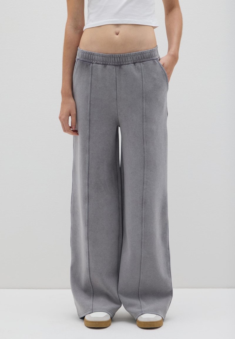 Weite graue Sweatpants mit elastischem Bund, seitlichen Taschen und kontrastierenden Nähdetails. Weicher Stoff und lockere Passform.
