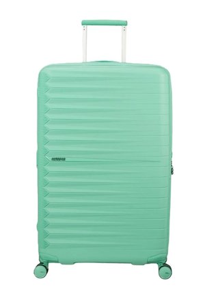 Grande valigia rigida verde menta con scanalature orizzontali testurizzate, manico telescopico e quattro ruote girevoli.
