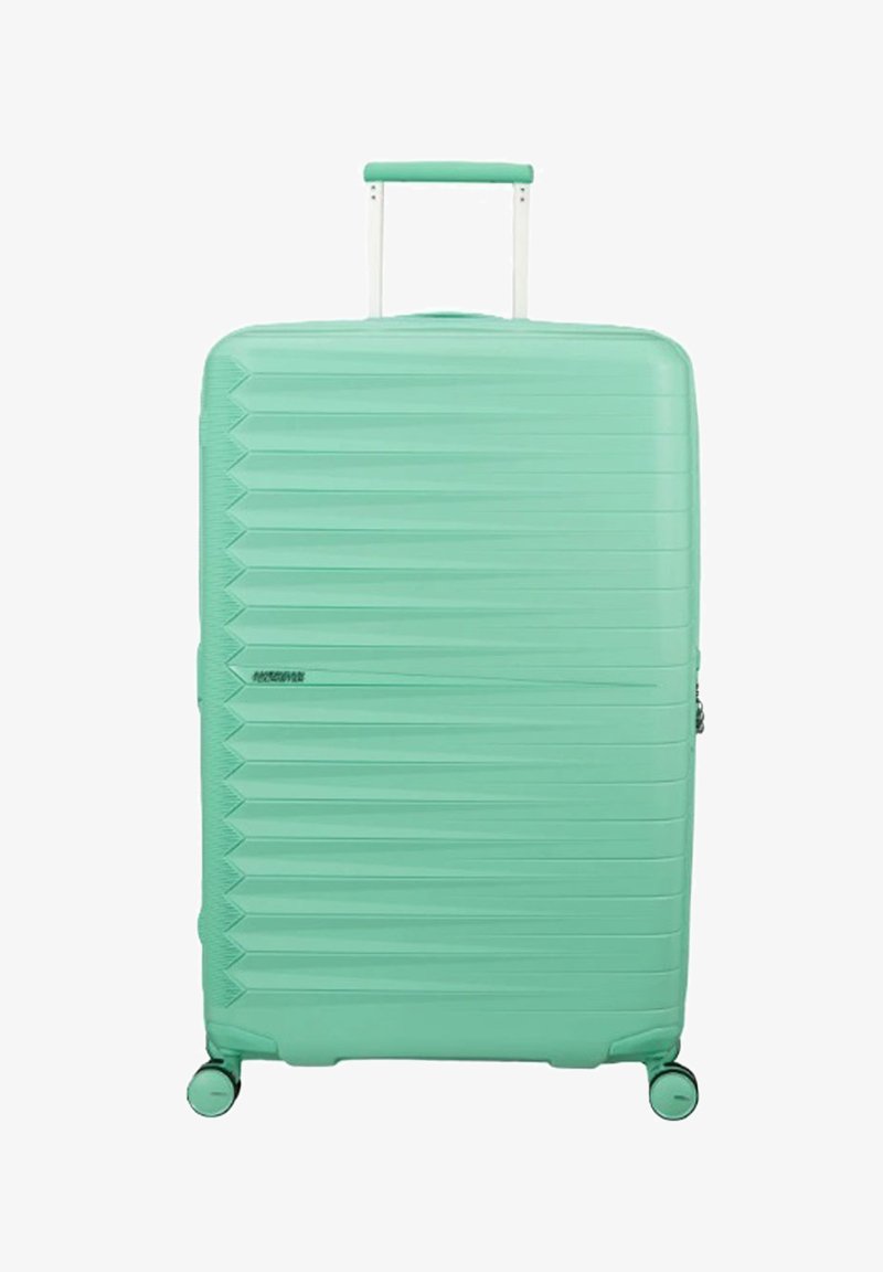 Grande valise rigide vert menthe avec des rainures horizontales texturées, une poignée télescopique et quatre roues pivotantes.