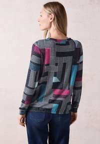 Svetr s dlouhým rukávem, který se vyznačuje geometrickým vzorem v černé, tyrkysové a purpurové barvě na texturované tkanině. Kulatý výstřih a uvolněný střih.