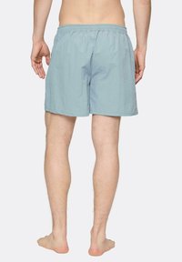 Svetlomodré plavky s elastickým pásom, vyrobené z ľahkého materiálu. Majú jednoduchý dizajn a strih po kolená.