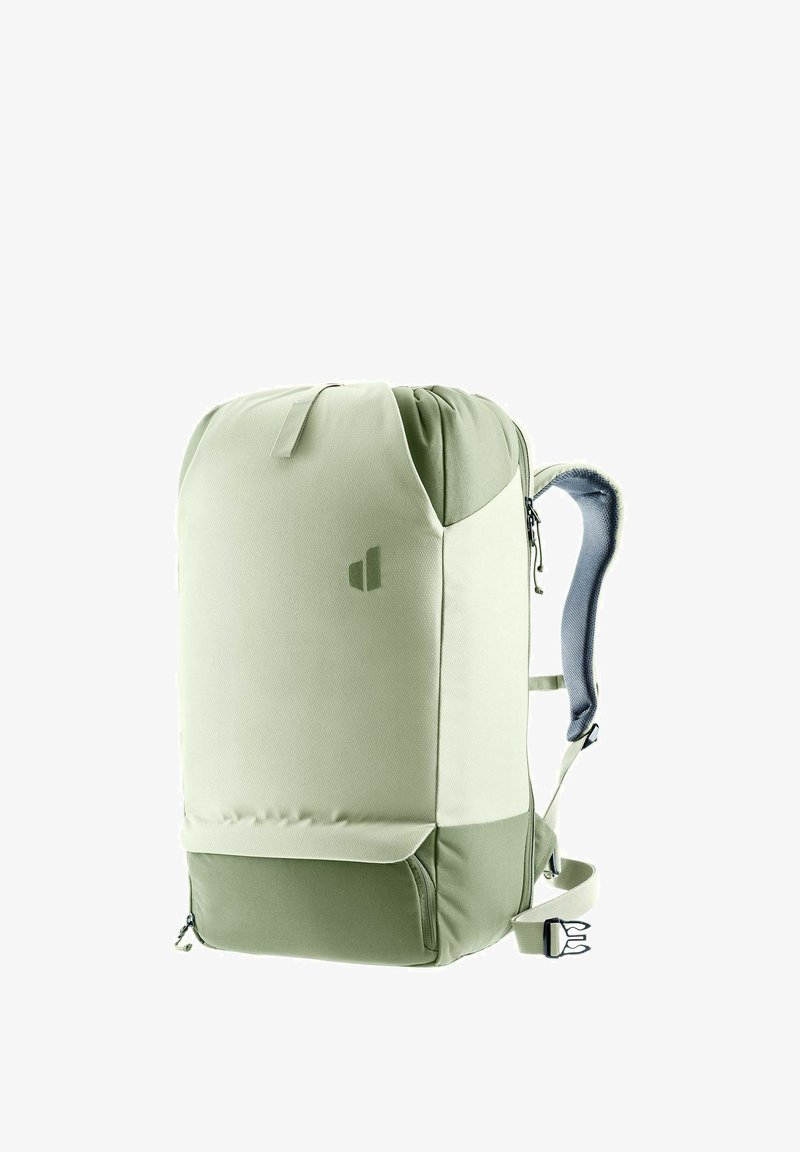 Sac à dos vert clair avec une texture lisse, une forme arrondie, des bretelles grises rembourrées et un compartiment zippé à l'avant. Présente un détail de logo.