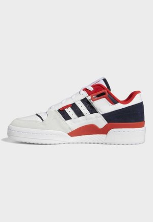 Hvid lav sneaker med marineblå og røde accenter, sorte striber på siden og hvide snørebånd på en ensfarvet baggrund.