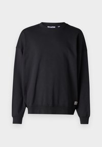 Black sweatshirt with long sleeves, crew neckline, ribbed cuffs, and hem. Made from soft fabric, features a small logo patch at the bottom.