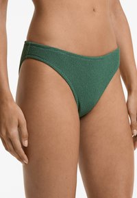 Mörkgrön bikiniunderdel med texturerad tyg. Har en låg midja och minimal täckning med släta kanter. Perfekt för badkläder.