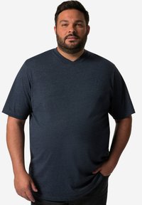 Tmavě modré v-neck tričko vyrobené z měkké, texturované tkaniny. Krátké rukávy a nenápadný logotyp na hrudi. Volný střih.